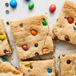 Colorful M&M cookie bars with chocolate chips on white background.