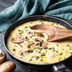 Creamy mushroom and thyme sauce cooking in a skillet with fresh herbs and mushrooms.