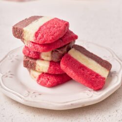 Colorful layered sugar cookies on a white decorative plate.