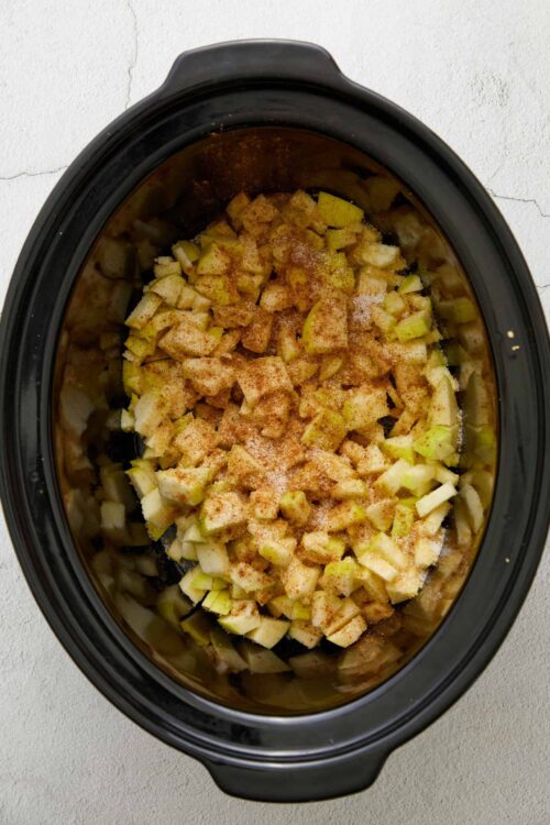 Cooked chopped apples and seasonings in a slow cooker for baking recipes.