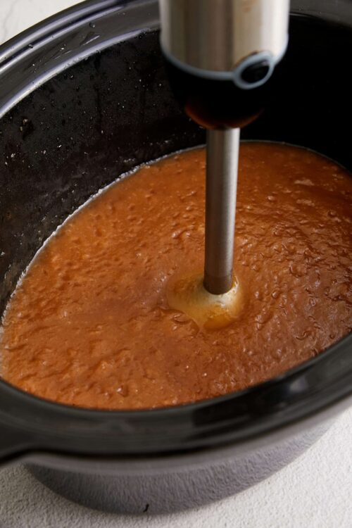 Creamy tomato sauce in a slow cooker with immersion blender.