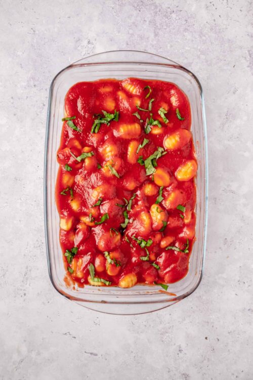 Creamy baked pasta with marinara sauce and fresh basil garnish.