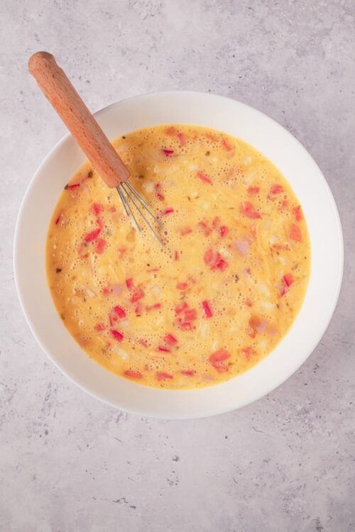 Creamy scrambled eggs with red bell peppers and onions, perfect for breakfast or brunch.
