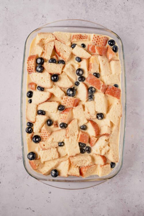 Butterscotch bread pudding with blueberries in a glass baking dish.