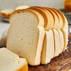 Soft homemade sponge cake with a golden brown crust, sliced on a rustic wooden board.