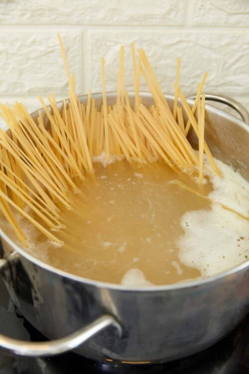 Dry spaghetti cooking in boiling water.