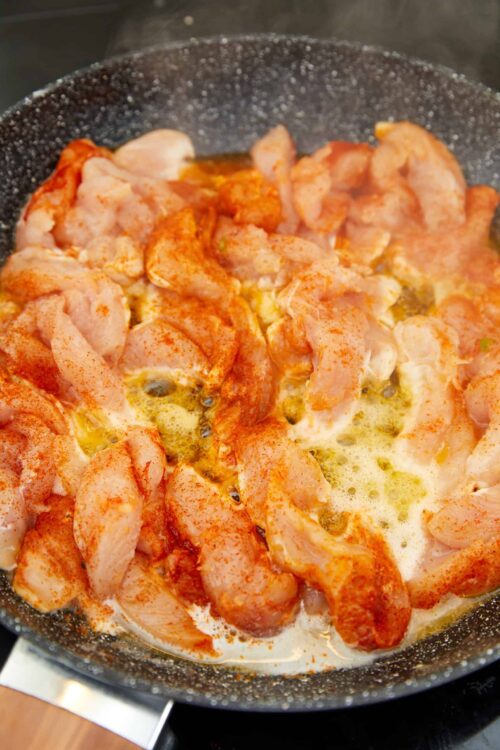 Creamy chicken being cooked with spices in a skillet.