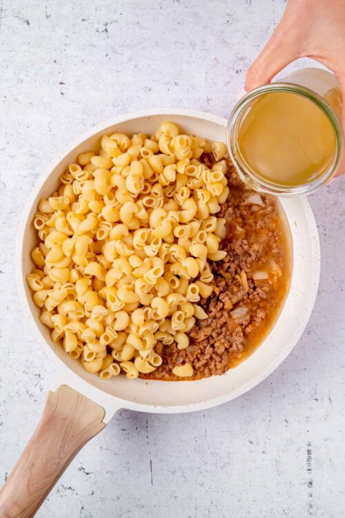 Creamy baked pasta with ground beef and savory sauce in a white skillet, ready for baking.