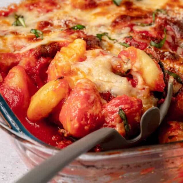 Roasted vegetable lasagna with cheese in a glass baking dish.
