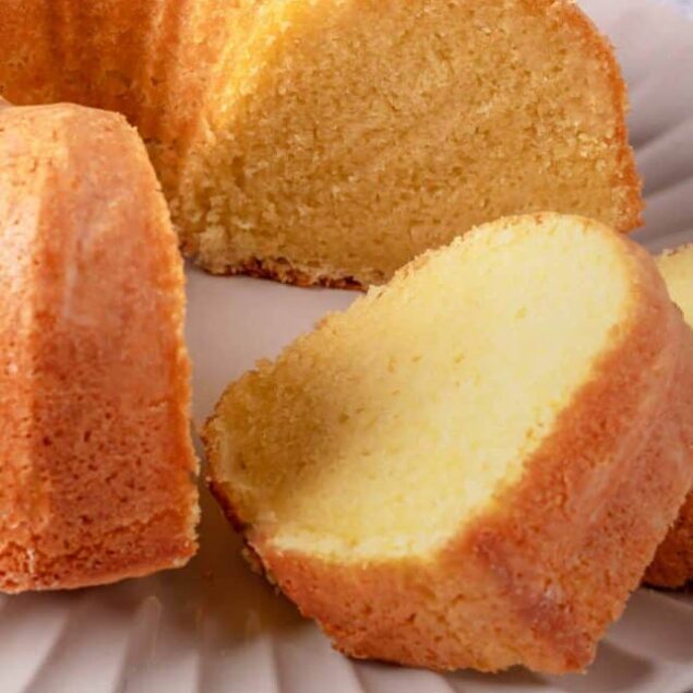 Fluffy vanilla bundt cake with golden crust on a white plate.