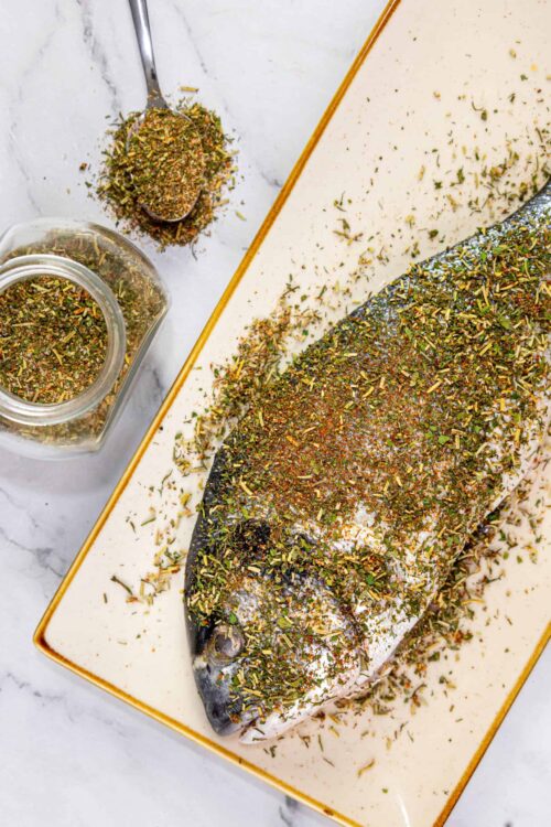 Freshly prepared whole fish seasoned with a colorful herb and spice rub, ready for baking or grilling.