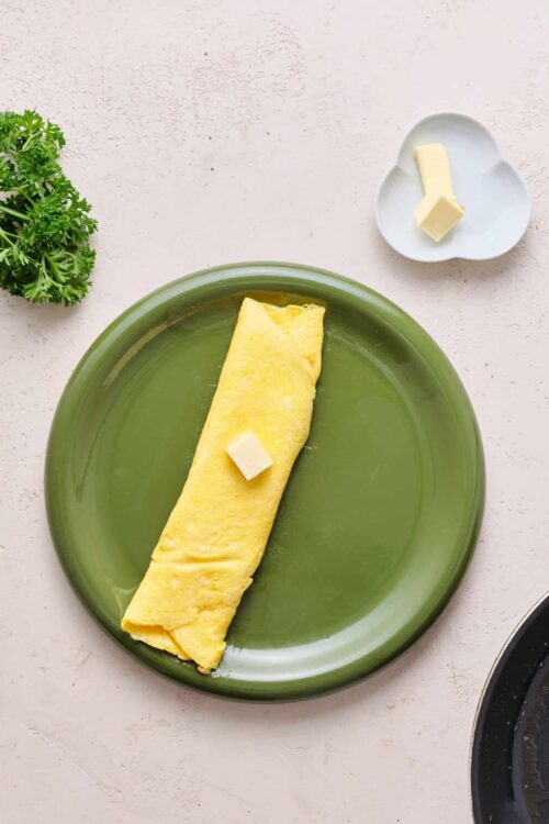 Fluffy scrambled eggs with butter on a green plate, perfect breakfast scene.