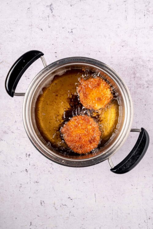 Golden fried cheese balls frying in hot oil, crispy appetizer recipe, baked bree.