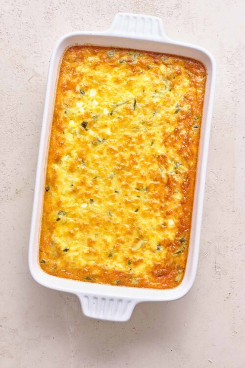 Baked creamy spinach and cheese casserole in a white baking dish.