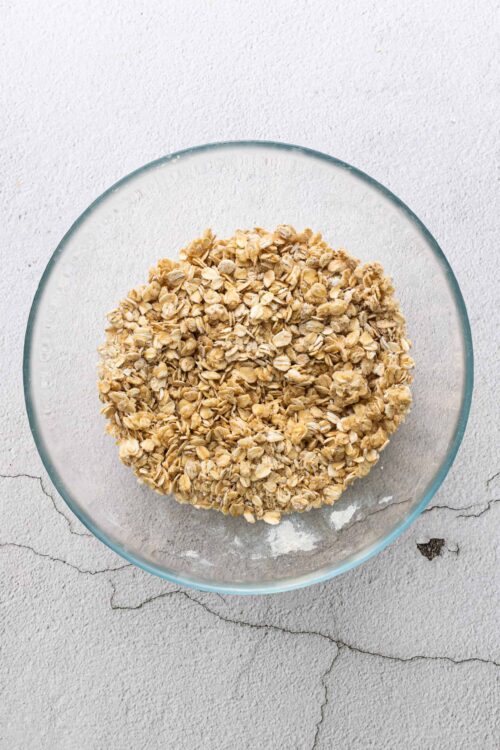 Oatmeal in a glass bowl on a textured surface.