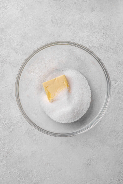 Butter and granulated sugar in a glass bowl for baking recipes.
