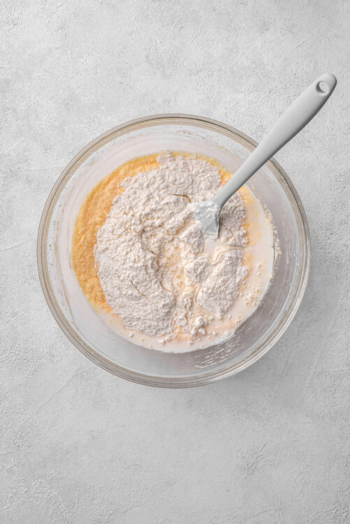 Flour and wet ingredients in a glass mixing bowl for baking, ingredients preparation for baking desserts.