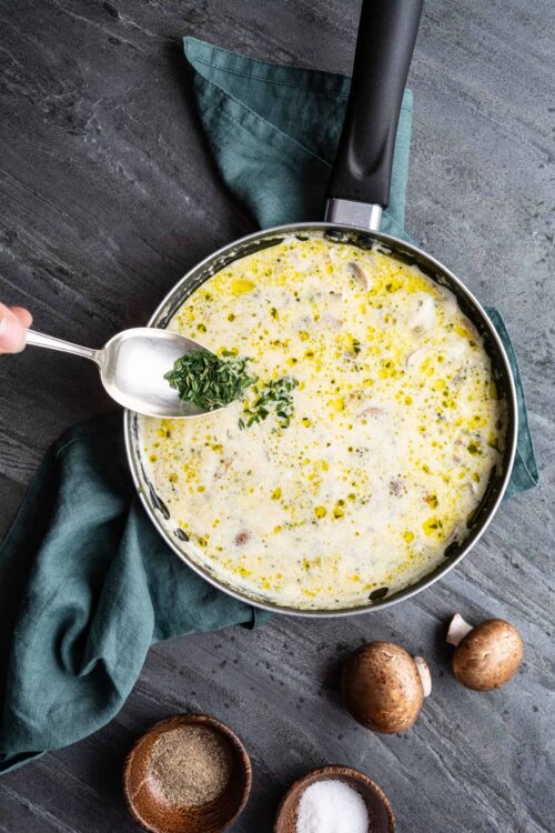 Creamy mushroom and herb soup in a black skillet with fresh thyme.