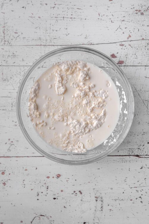 Flour and milk mixture in glass bowl, baking ingredients for bread or cake.