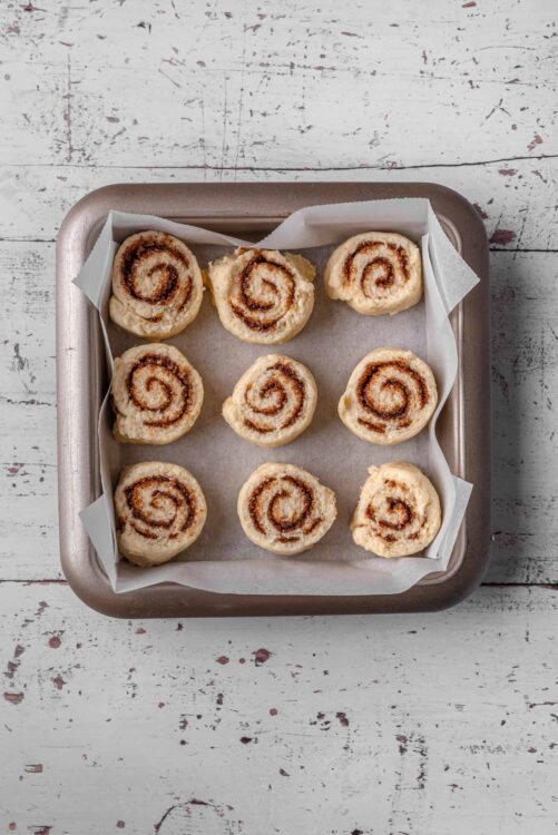 Sweet cinnamon roll dough ready for baking on parchment-lined baking sheet.
