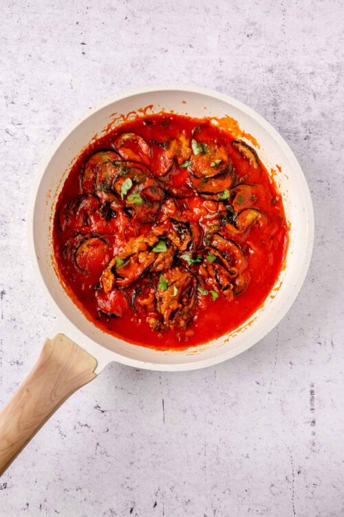 Fresh eggplant Parmesan in a white baking dish with tomato sauce and melted cheese.