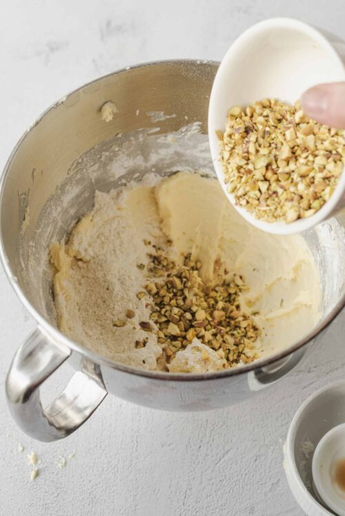Chopped nuts being added to cookie dough in a stand mixer.
