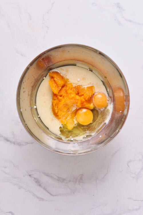 Creamy pumpkin and egg mixture for baking, prepared in a metal mixing bowl.