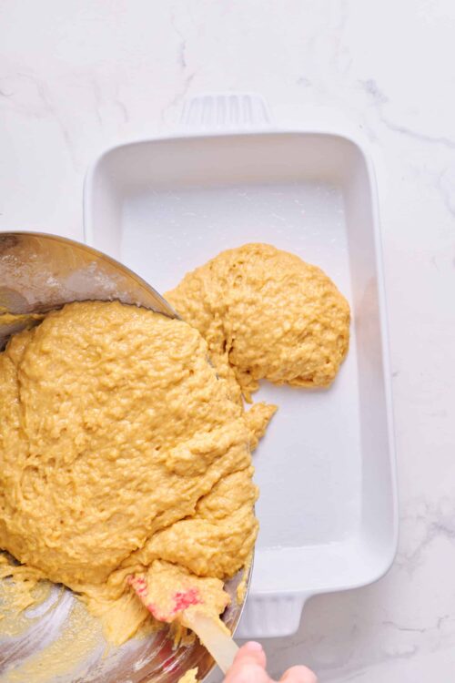 Creamy cornbread batter being poured into a baking dish for homemade cornbread.