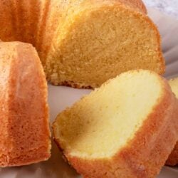 Fluffy vanilla bundt cake with golden crust on a white plate.