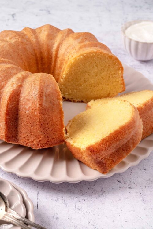 Light and fluffy vanilla cloud cake on a white scalloped plate. Perfect for homemade dessert recipes and special occasions.
