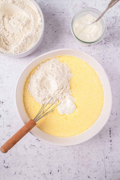Flour, cornmeal, and yogurt in mixing bowls for homemade baking recipes.