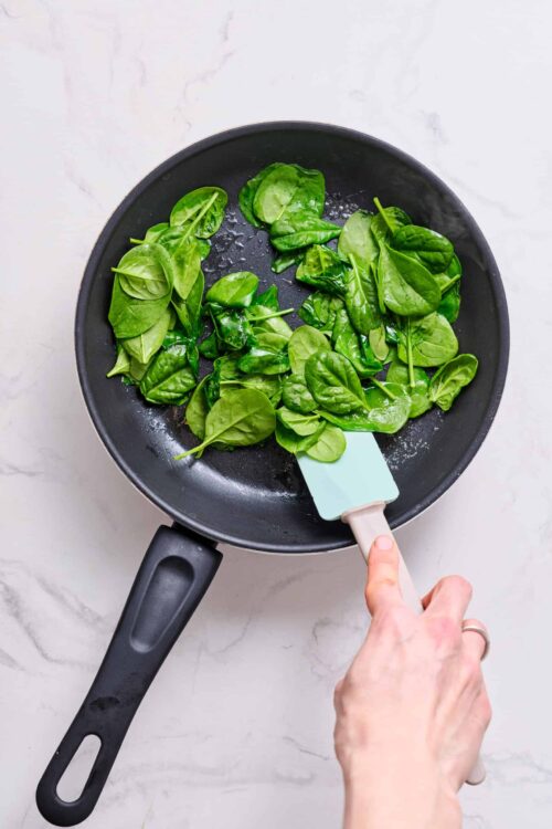 Fresh spinach in a non-stick frying pan for cooking or sautéing.