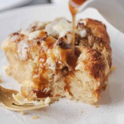 Buttery cinnamon rolls with melting cream cheese icing on a white plate.