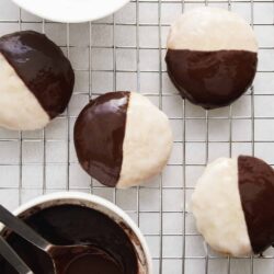 Decadent half-dipped chocolate and vanilla cookies cooling on a wire rack.