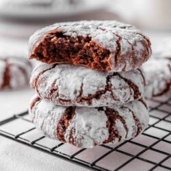 Soft-baked chocolate crinkle cookies dusted with powdered sugar on cooling rack.