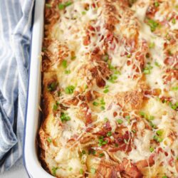 Cheesy bacon breakfast casserole with hash browns and green onions in a baking dish.