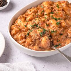 Creamy chicken and potato stew in a white bowl, garnished with fresh parsley.