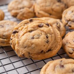 Buttery chocolate chip cookies with golden edges on a cooling rack.