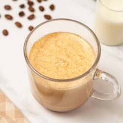 Creamy iced coffee with a frothy top, served in a clear glass mug. Often enjoyed as a refreshing summer beverage or breakfast boost.