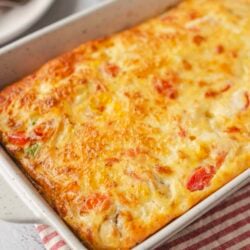 Cheesy baked casserole with vegetables and golden crust in white baking dish.