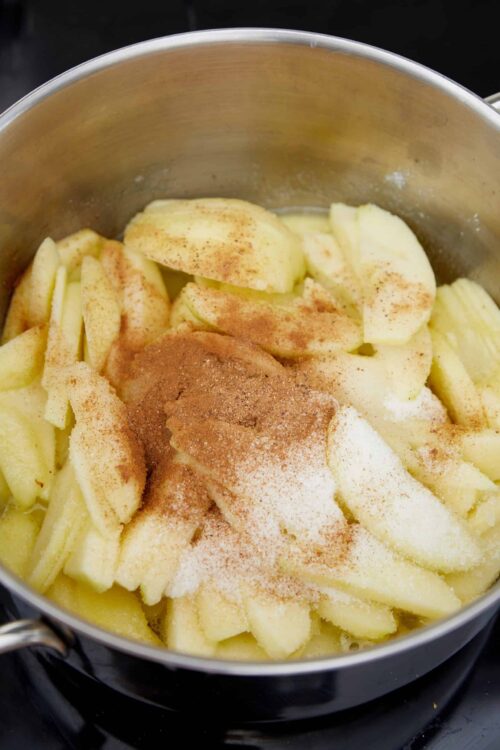 Sliced apples with cinnamon and sugar in a saucepan for apple pie filling.