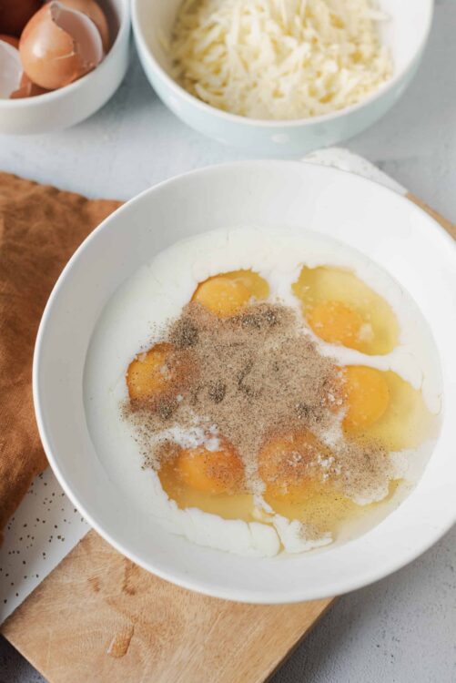 Eggs with seasoning in a white bowl for baking or cooking recipes.