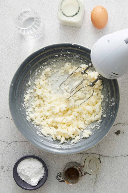 Creamy mashed potatoes being prepared with an electric mixer in a bowl.