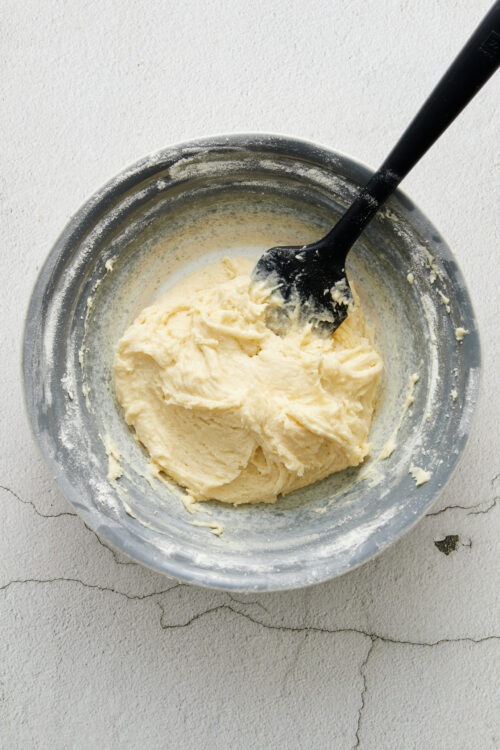 Creamy vanilla cake batter in a mixing bowl with a spatula.