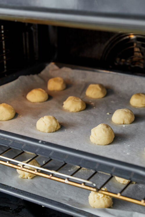 Small cookie dough balls on baking sheet in oven, ready to bake, homemade dessert baking, baked goods preparation, Baked Bree.
