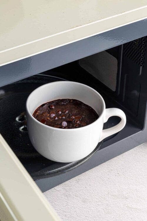 Hot chocolate being heated in microwave mug for baking and dessert recipes.