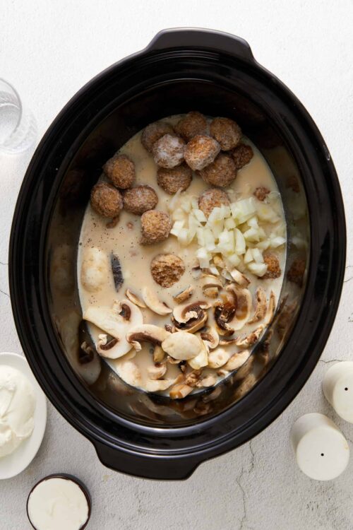 Creamy slow cooker beef stew with mushrooms, onions, and meatballs in a savory broth.