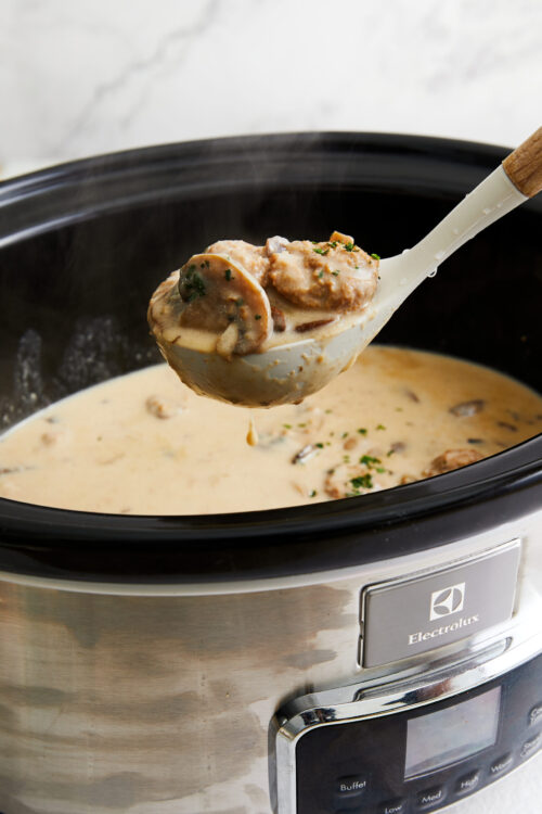 Creamy mushroom and beef stew cooking in electric slow cooker.