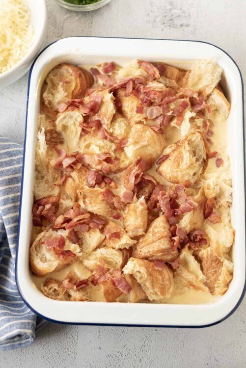 Crispy garlic bread casserole with bacon and cheese, baked in a white dish.