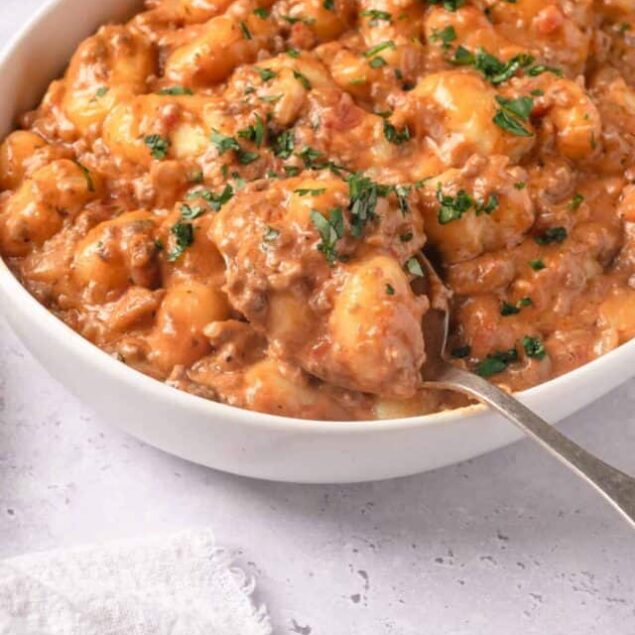 Creamy chicken and potato stew in a white bowl, garnished with fresh parsley.